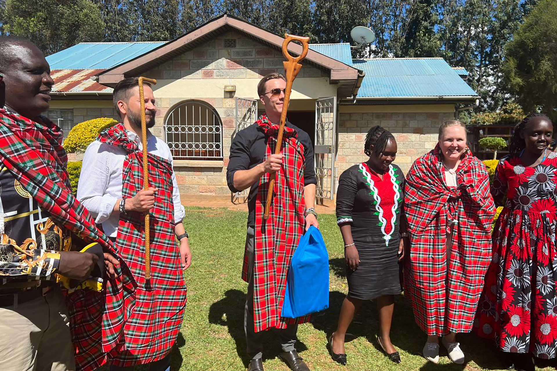Sanna, Peter ja Janne mukana kenialaisissa juhlissa punaruudulliset kaavut yllään.
