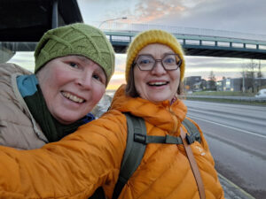 Pipopäiset Kaisa ja Kristina ottavat selfien tien vieressä.